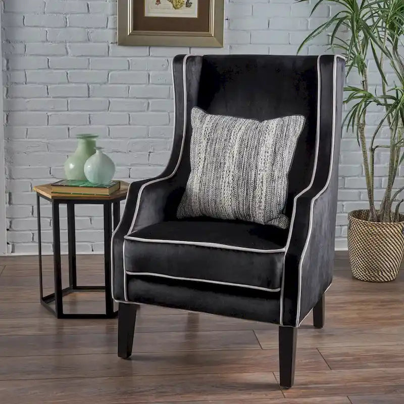 Poltrona decorativa con schienale alto e ali, rivestita in velluto, bordino bianco e gambe in legno nero