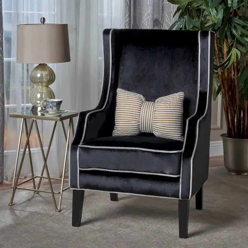 Poltrona decorativa con schienale alto e ali, rivestita in velluto, bordino bianco e gambe in legno nero
