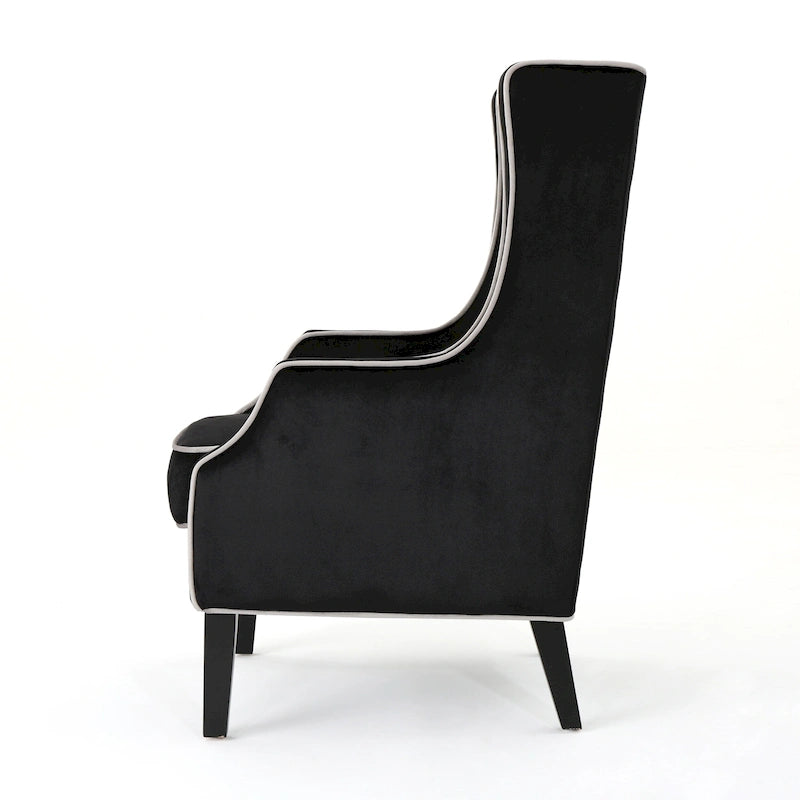 Poltrona decorativa con schienale alto e ali, rivestita in velluto, bordino bianco e gambe in legno nero